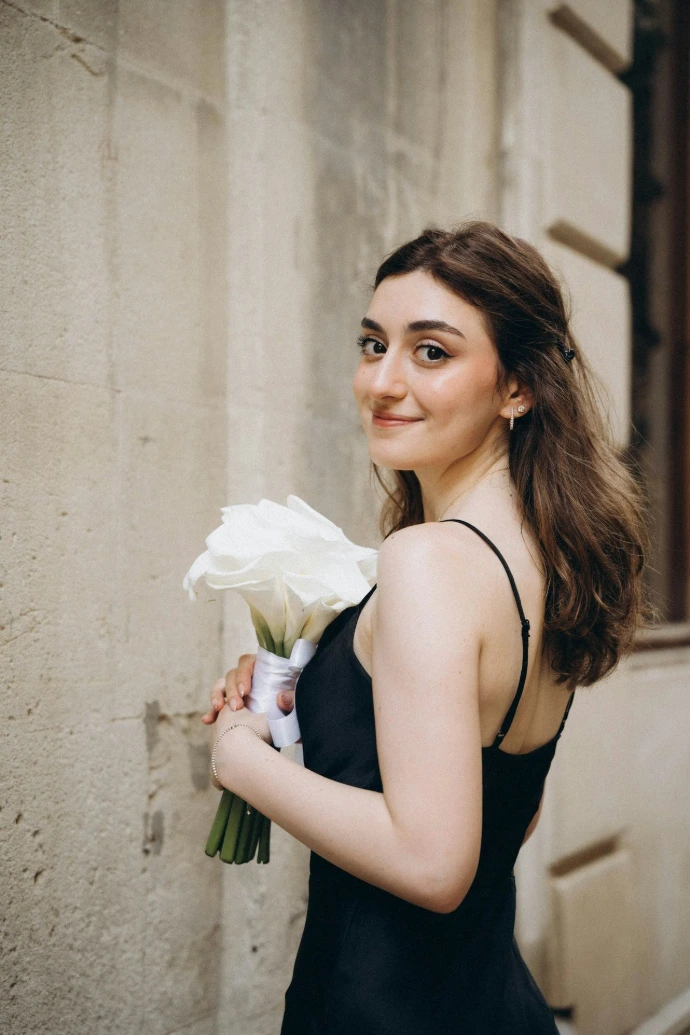A woman in a black dress holding a bouquet of flowers